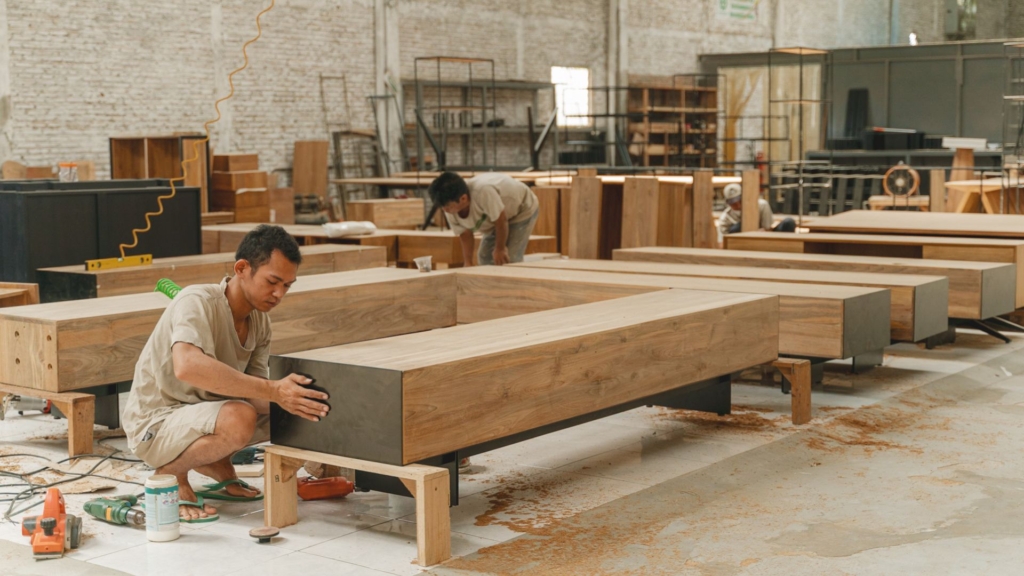 A person refurbishing furniture in a warehouse